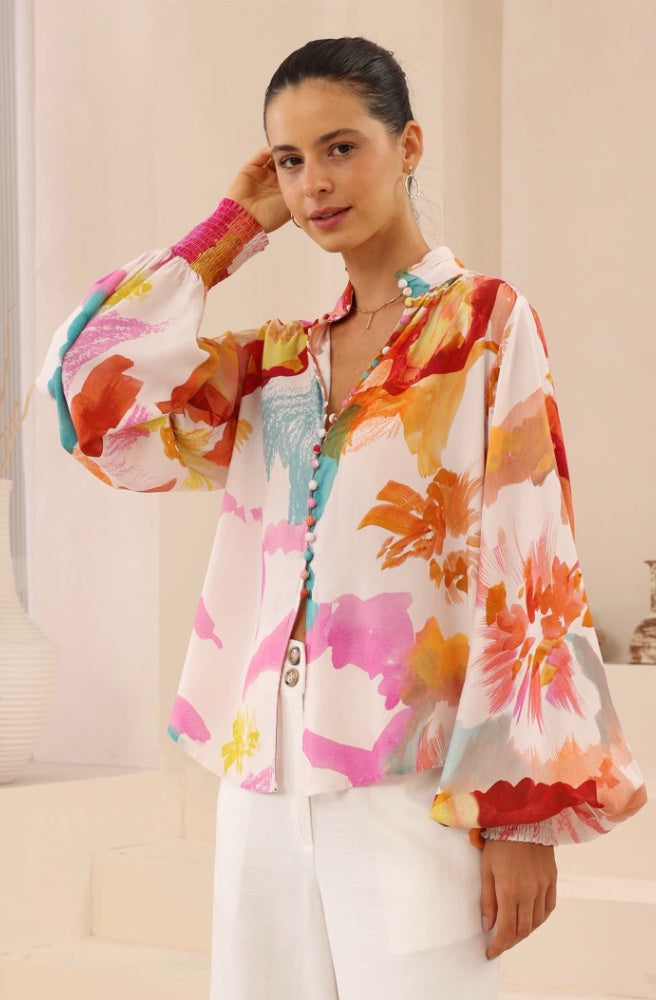 Fresco Bloom Blouse, Woman wearing a colourful floral blouse with a neutral background
