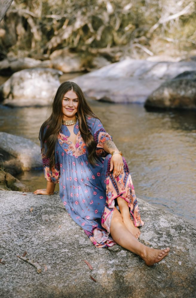 Woman in a floral dress sitting on a rock by a stream Jaase dress