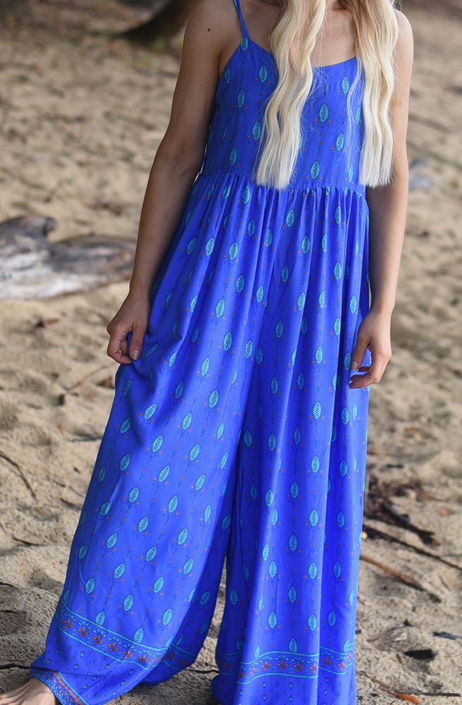 Woman wearing a blue pantsuit with a pattern on a sandy background
