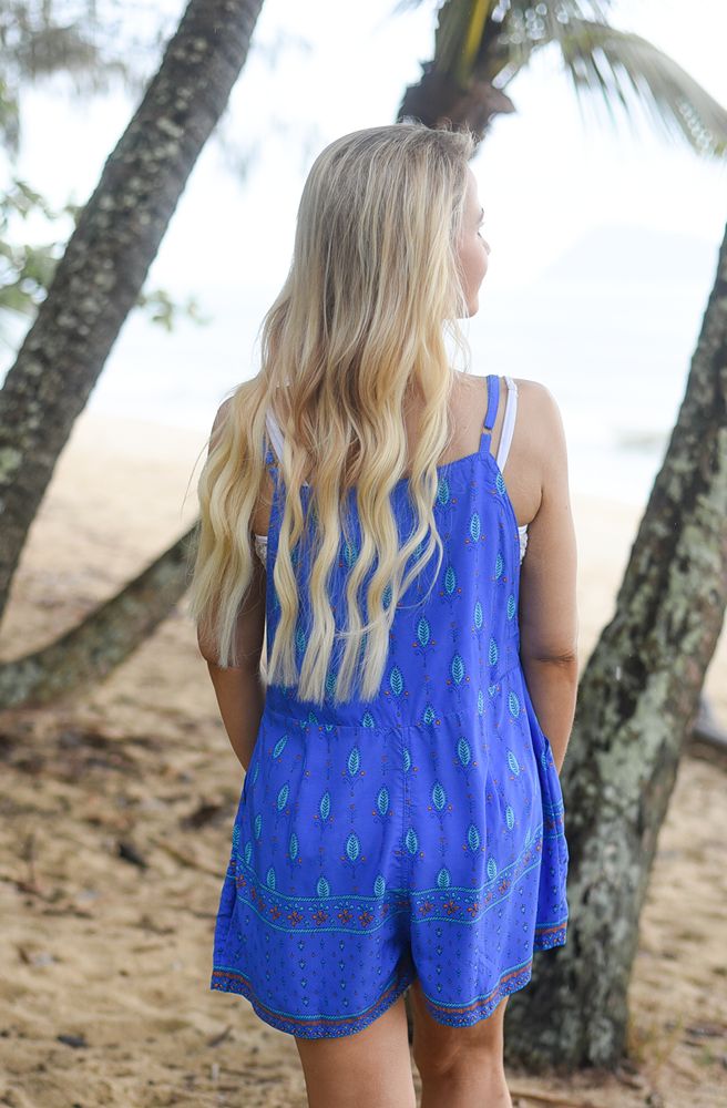 Woman wearing a blue overalls backview with green patterns in a natural setting