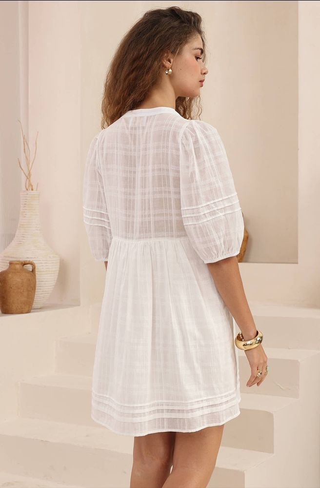 Woman wearing a white dress in a neutral setting