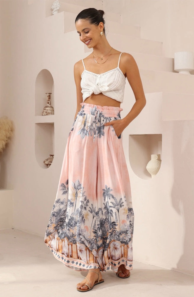 Palma Rosa Maxi Pants, Woman wearing a white cami top and soft pink maxi pants in a minimalistic room.