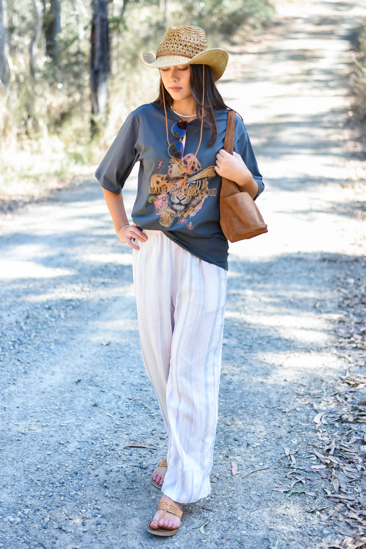 Front view of the Blush Horizon Stripe Pants featuring blush and cream vertical stripes, an elastic waistband and relaxed wide legs.