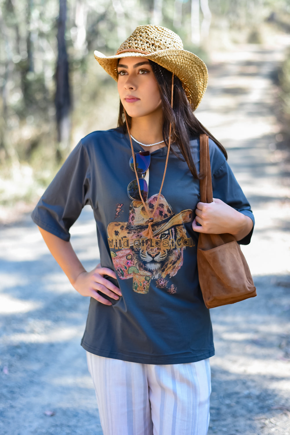 Front view of the Charcoal Last Call Tee featuring a colourful cowboy cat graphic on a charcoal-blue background. Paired with Crochet Tan Sun Hat
