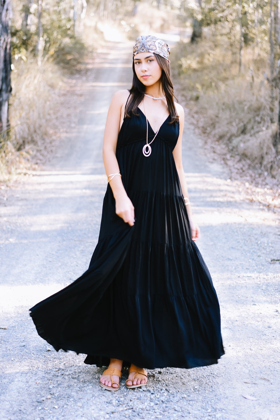 Ebony Umbrella Dress featuring a classic black maxi silhouette, a deep V neckline and a voluminous flowing tiered skirt.