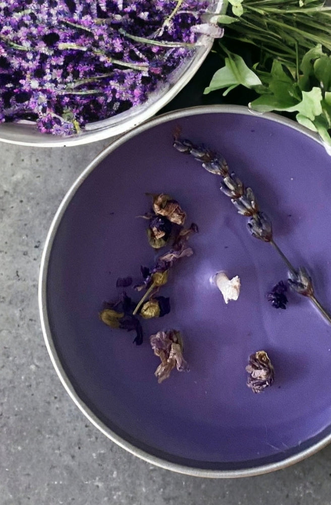 French Lavender Soy Candle in a purple tin with dried lavender and botanical accents.