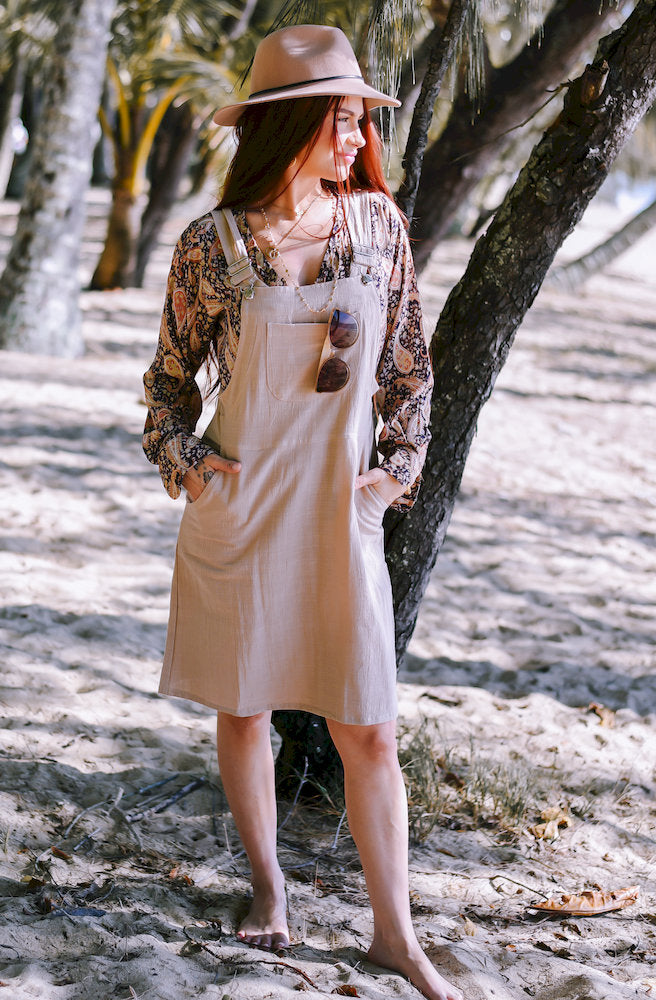 Gypsy Thread Pinafore Mid Short Cream featuring a relaxed knee-length silhouette, adjustable shoulder straps and practical pockets.