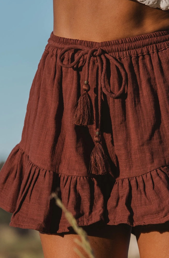 Close-up of the Mary Chocolate Cotton Shorts showing the textured cotton fabric, adjustable tassel drawstring and gathered ruffle detailing.