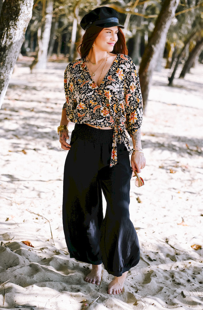 Seraphina Shazza Top in a black floral print with warm yellow, orange and mustard tones, elasticated waist and side tie.