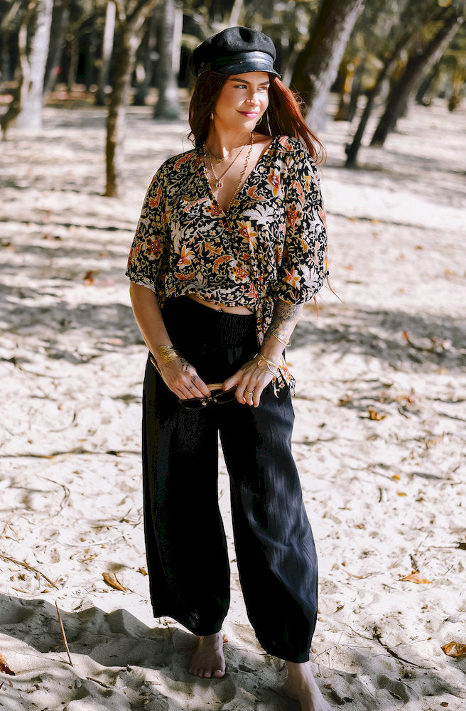 Seraphina Shazza Top featuring a bold floral print on a black base with a flattering V neckline, wide sleeves and faux-wrap styling.