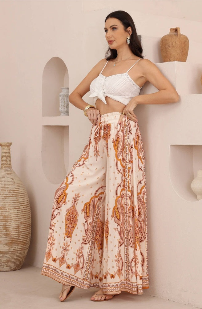 Sienna Paisley Maxi Pants featuring a peachy-ivory base, rust and caramel paisley print, and flowing wide legs.
