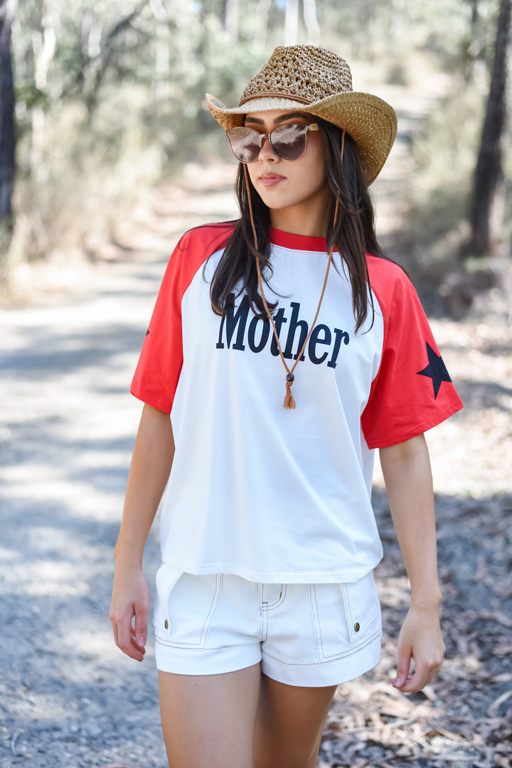 Front view of the White Mother Tee featuring navy Mother lettering on a white body with red raglan sleeves, red neckline and navy star details.