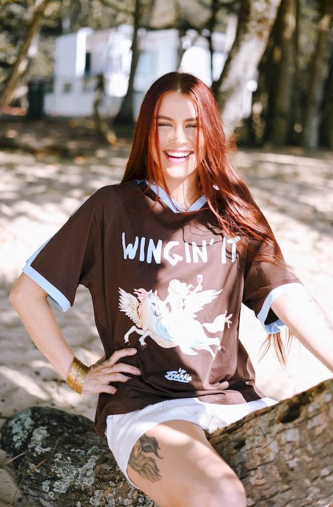 Wingin It Brown Tee showing the relaxed oversized fit with light blue shoulder stripes and sleeve trims.
