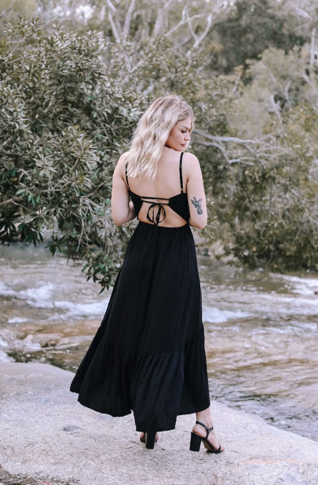 Tee wearing the Ebony Sophia Maxi Dress featuring an open tie-back and flowing black rayon skirt